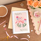 Personalised A5 notebook with flamingo design on the cover, placed on a desk next to a cup of coffee, pens, and decorative ribbons.