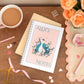 Personalised A5 notebook with a peacock design on the cover, placed on a desk next to a cup of coffee, a pen, and some decorative ribbons.
