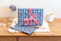 Abstract Blue patterned gift wrapping with a pink bow on a wooden surface with stationery items.