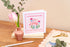 Wedding card with flamingo design on a table with flowers and cake