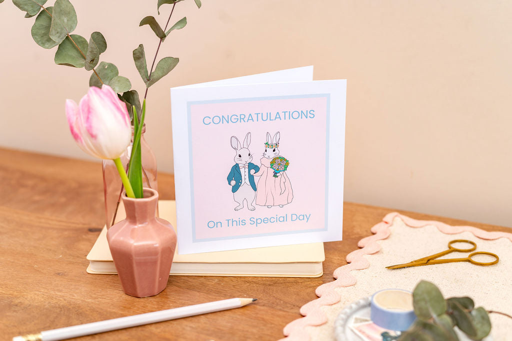 Wedding Special Day Congratulations card with a vase of flowers and a cake on a wooden table.