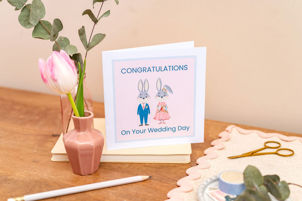 Wedding card with couple illustration on a table with flowers and cake
