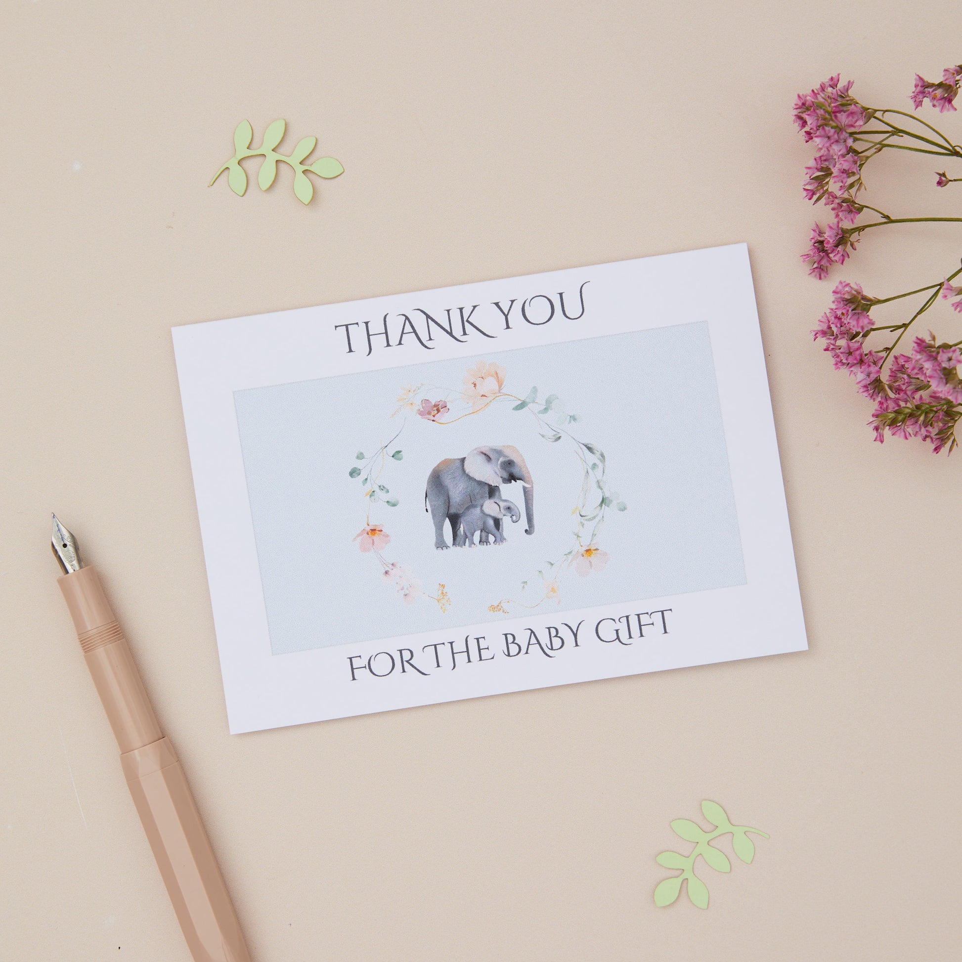 Baby Elephant surrounding by a floral ring,on a blue background .The card says thank you for the baby gift. The card is on a neutral background with stationery elements