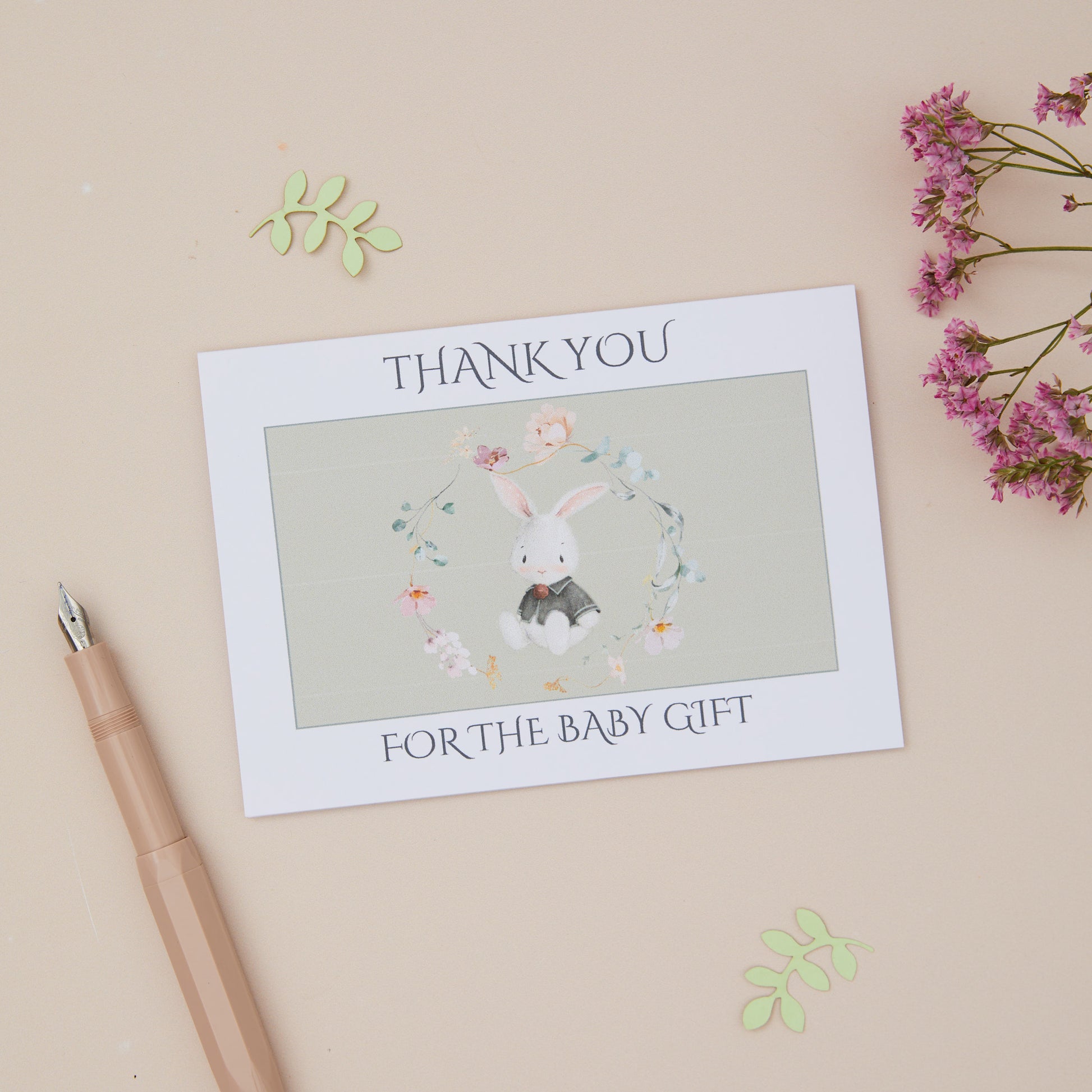 Baby Gift Card, featuring a bunny rabbit sitting within a delicate floral ring. T/he card says, thank you for the baby gift. The card is set on a neutral background.