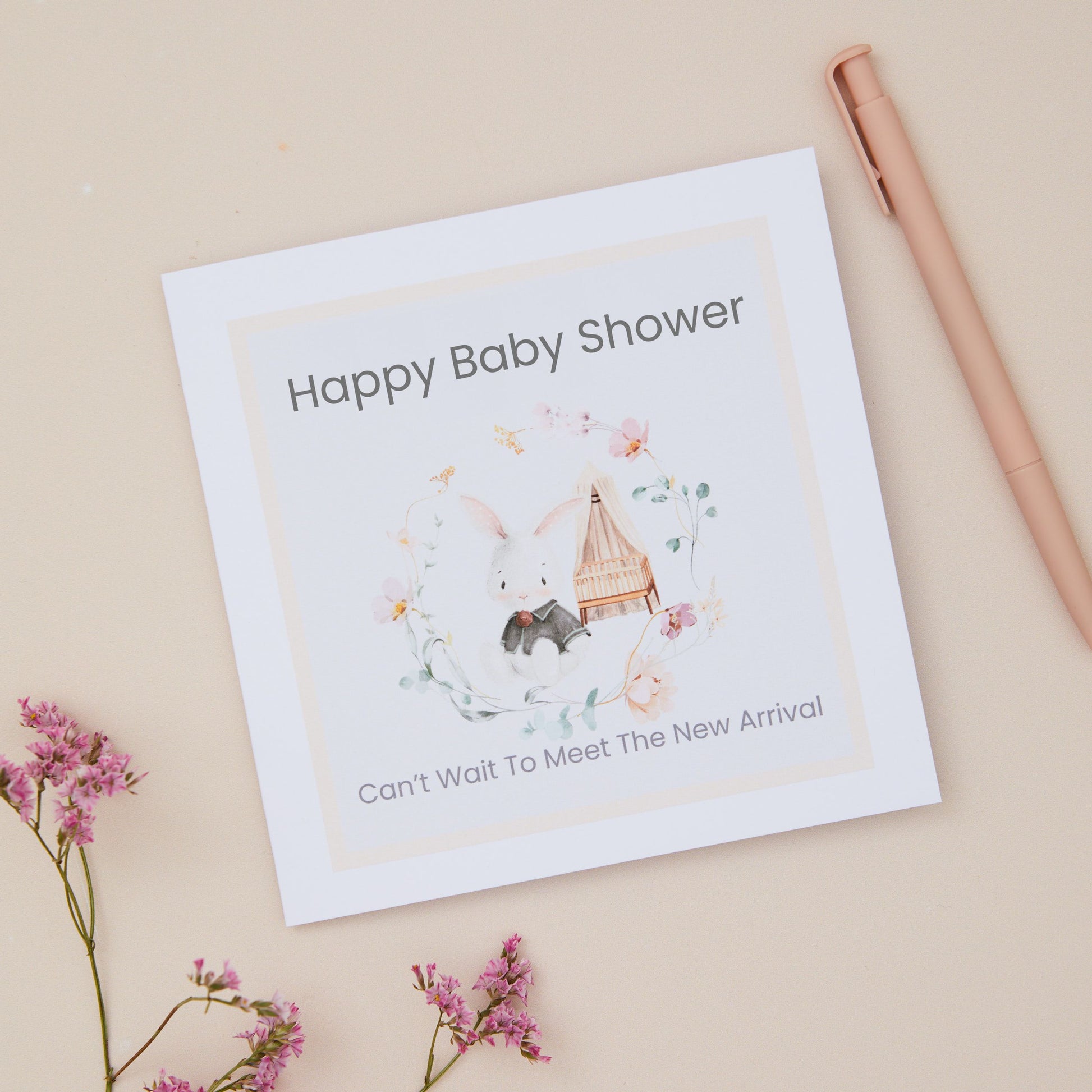 Baby shower card with illustrations of a baby Rabbit and crib circled by a floral design on a beige background