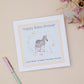 Baby shower card with zebra illustration and text that says happy baby shower, can't wait to meet the new arrival. The cards sits on a beige background