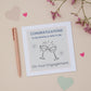 A Brother and wife to be Engagement Congratulations Card featuring two celebratory glasses against a pastel background, with a pink dried flowers bunch, a pink pen, and decorative hearts.