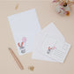 Bunny Rabbit Letter Writing Set with a rabbit illustration and pink balloon on a beige surface with stationery items.