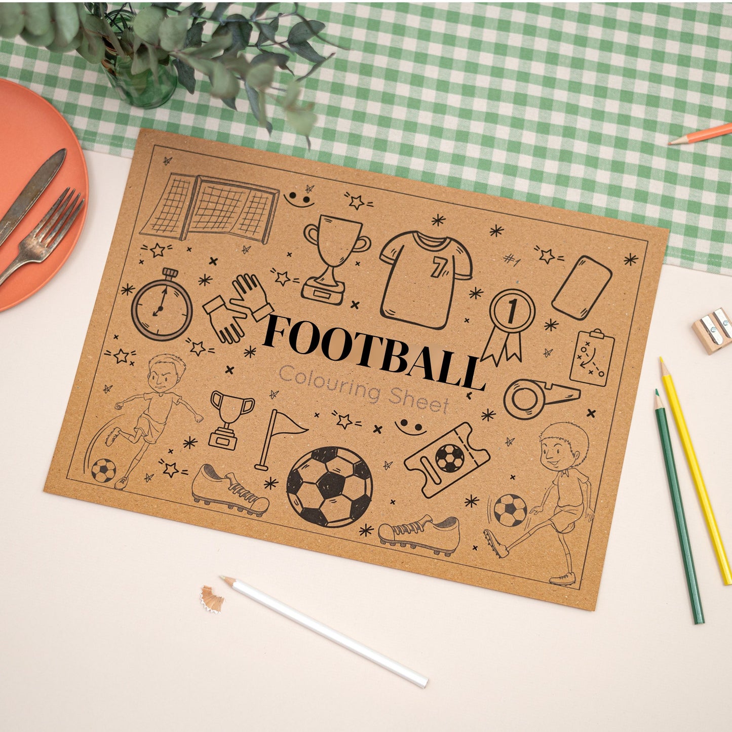 Children's Colouring In Football-themed Placemat. The Mat says the words "Football" in the middle. The Mat sits on a checkered tablecloth with stationery items.