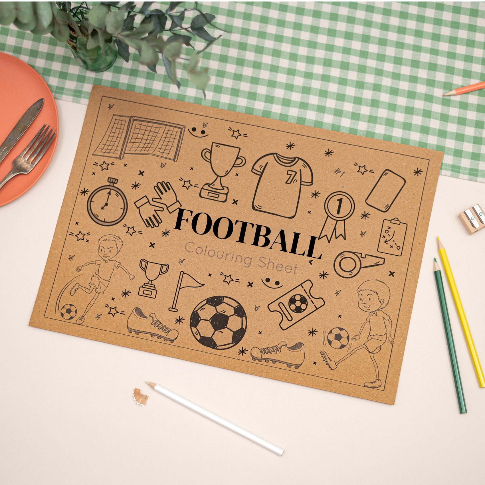 Children's Colouring In Football-themed Placemat. The Mat says the words "Football" in the middle. The Mat sits on a checkered tablecloth with stationery items.