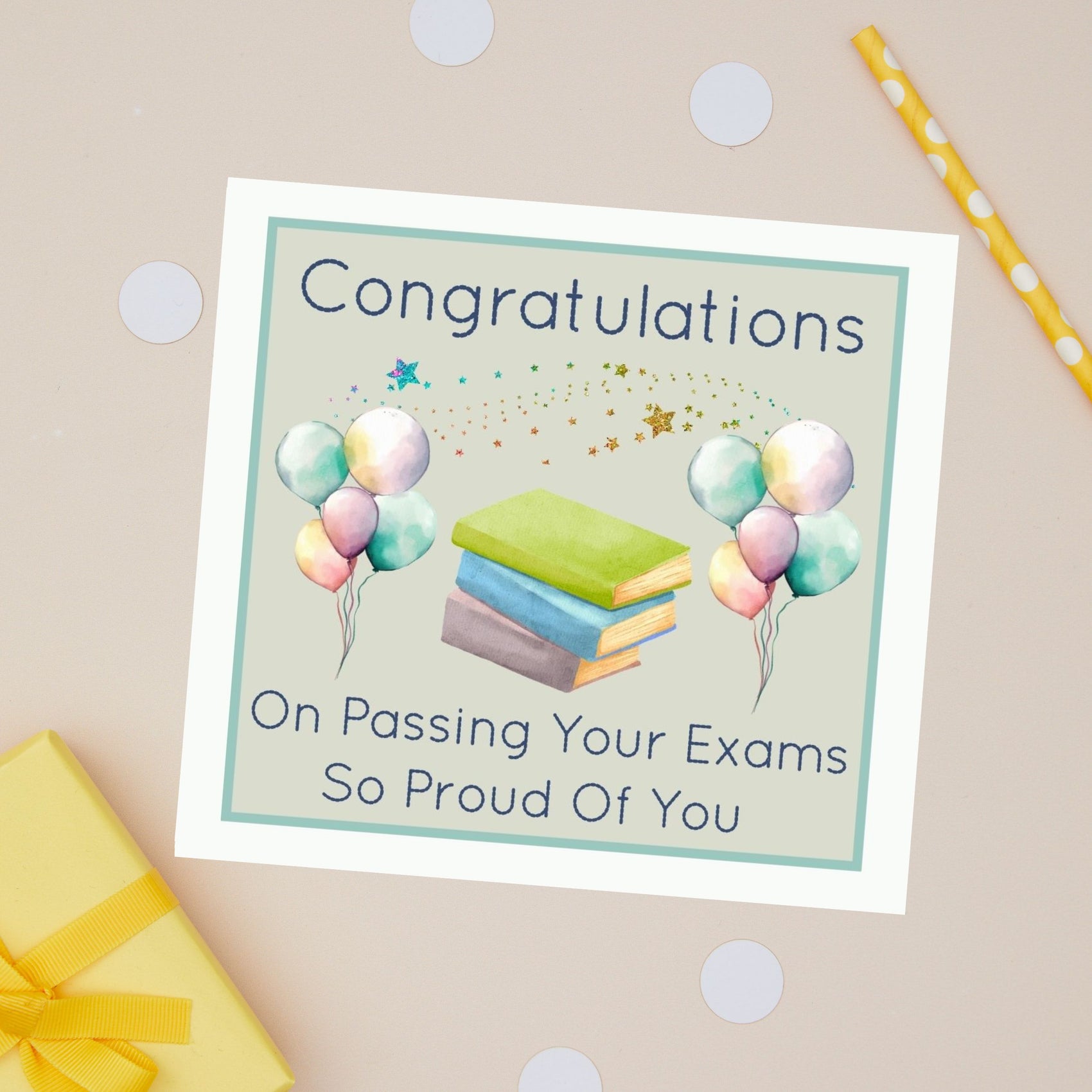 Congratulations on passing exam card with an illustration of a pile of books and multi coloured balloons on either side. there is a star burst of sprinkles across the card
