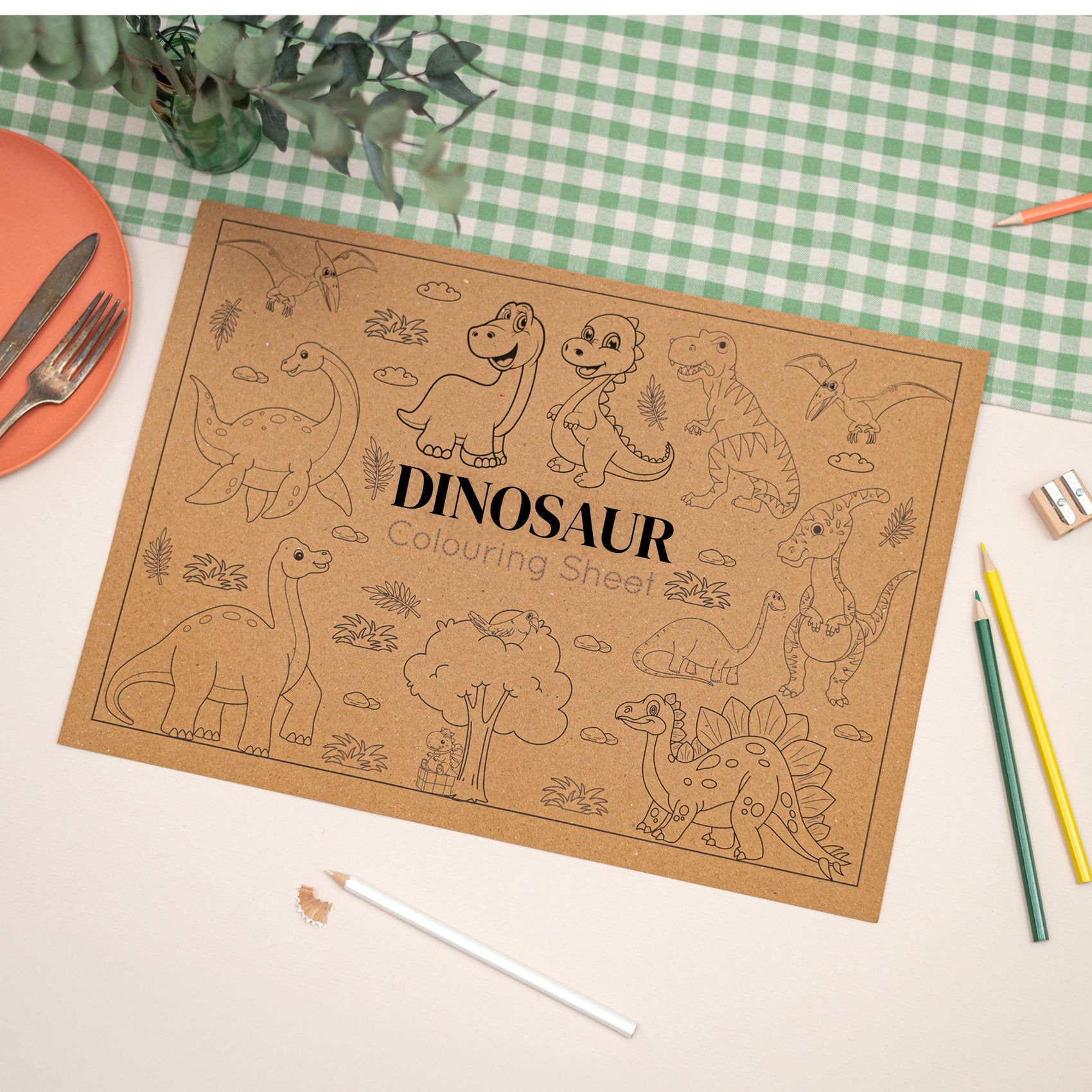 Kids Dinosaur colouring Mat. Mat illustrates different types of cartoonn style dinosaurs. The Colouring mat is made with Kraft Brown Eco Friendly paper. The Mat is on a table with coloring supplies