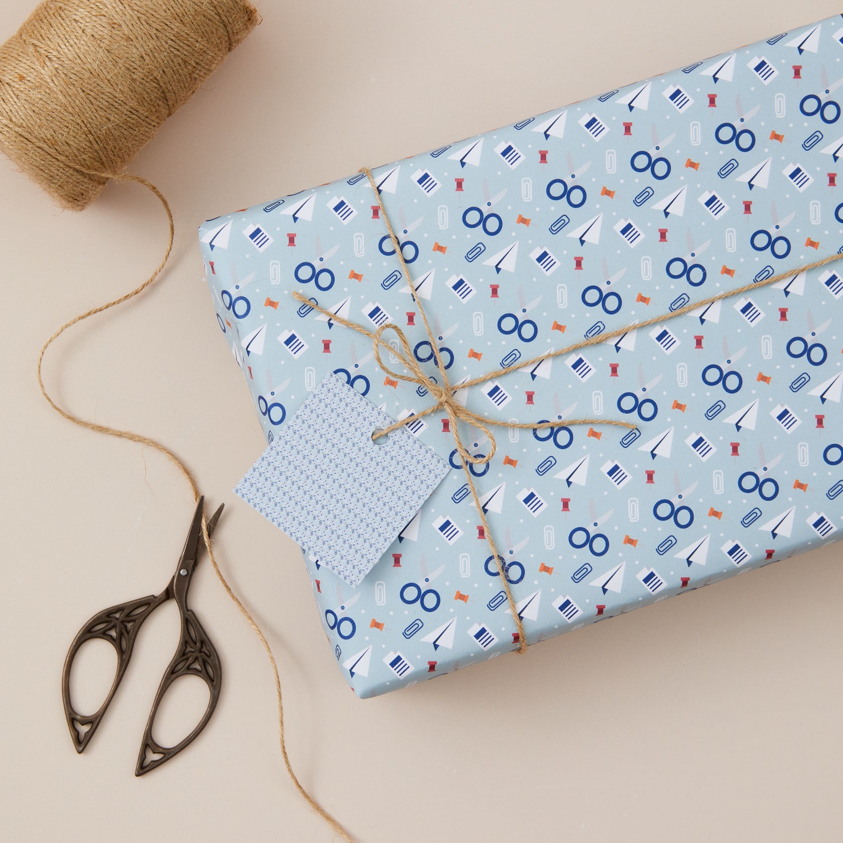 Gift wrapping of blue paper with scissors, stationery Design with twine on a beige background