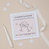 A Granddaughter  engagement congratulations card with two glasses toast design, including two celebratory glasses, accompanied by sparklers. The card is presented on a neutral background, with a decorative ribbon, confetti & pen. The Card features the text " Congratulations to our granddaughter & husband to be - on your engagement.