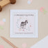 Congratulations on becoming a grandparent Greeting card with a zebra illustration surrounded by a floral circle on a pink background. &