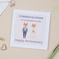 A Grandson Wedding Anniversary Card with an illustration of two foxes dressed in wedding attire, with a 'Congratulations Happy Anniversary' message, placed on a desk with stationery items.