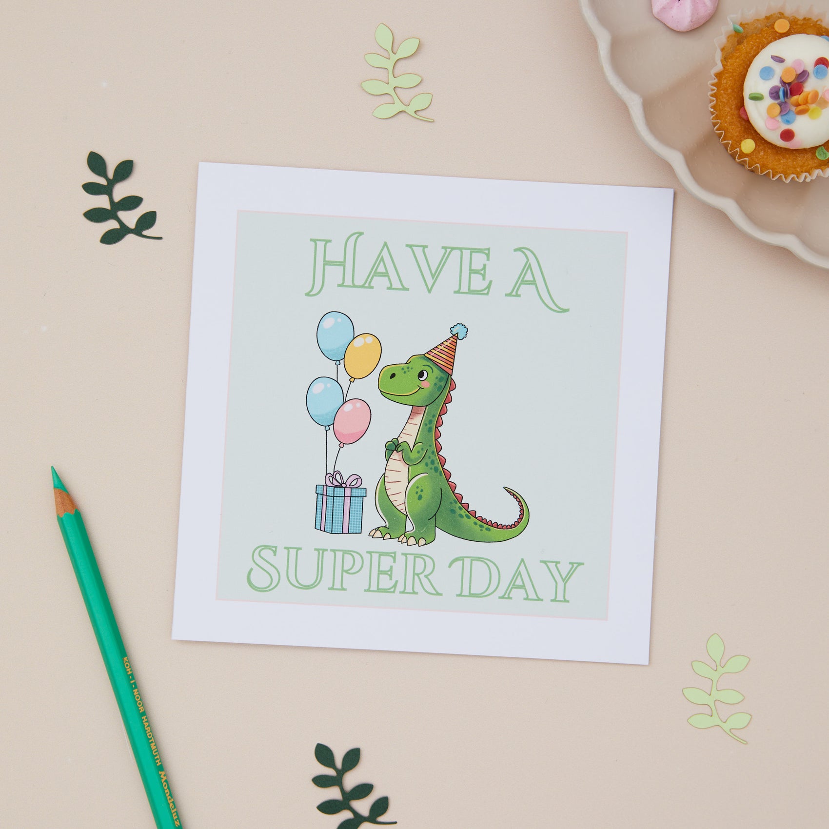 Kids Green Dinosaur Birthday greeting card with an illustration of a dragon holding balloons and a present, with the text 'HAVE A SUPER DAY' on a beige background. A green pencil and decorative elements are also visible.