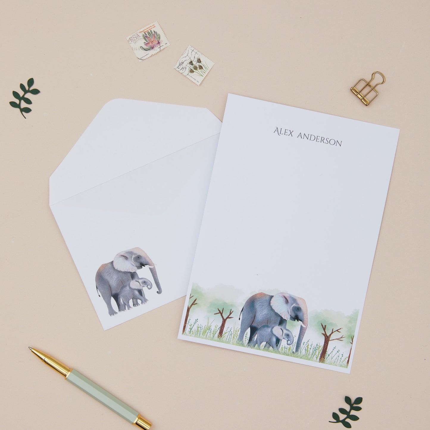 Personalised Letter Writing Set featuring an Elephant and their young within grassy land. Letter Writing Set with matching envelopes, on a beige background.