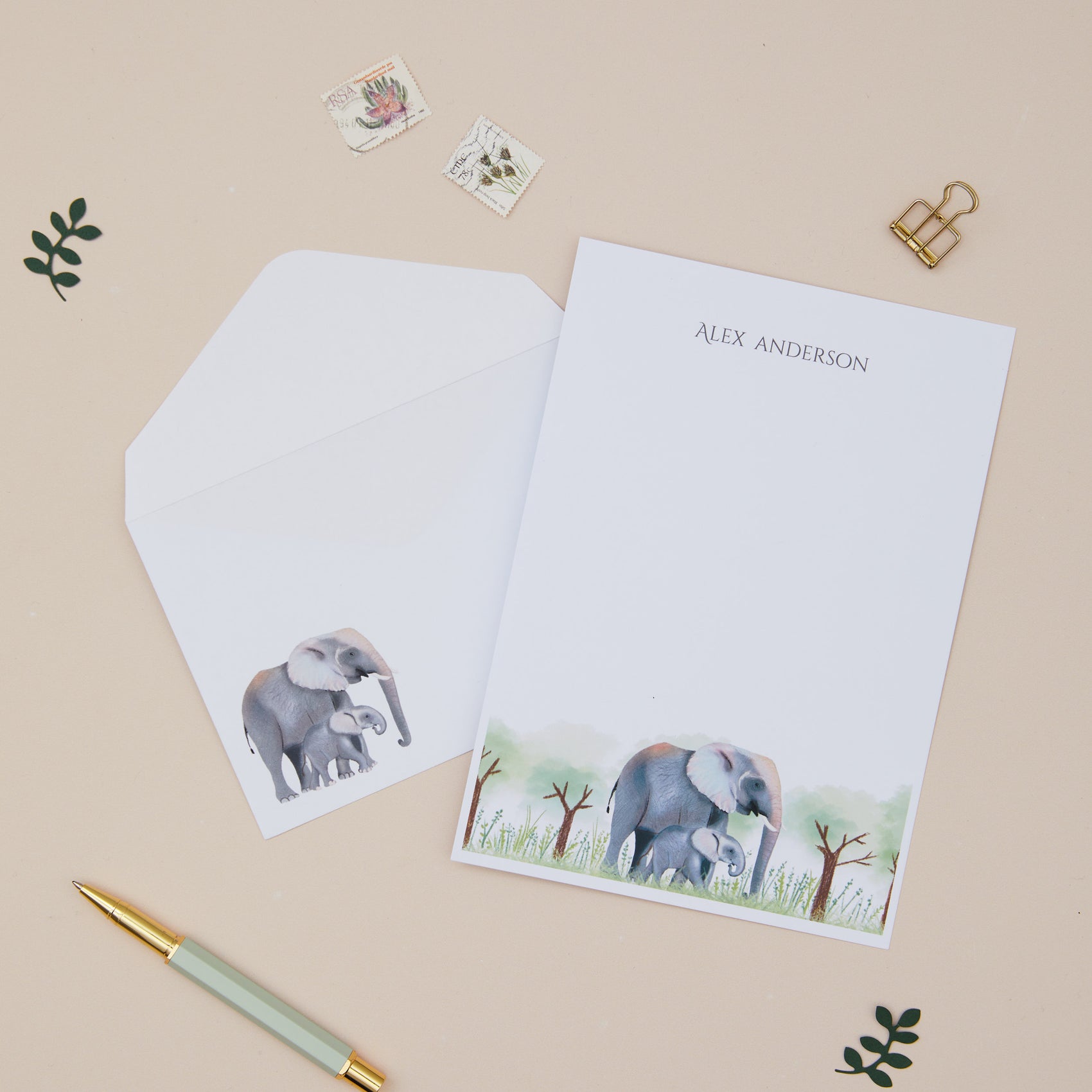 Personalised Letter Writing Set featuring an Elephant and their young within grassy land. Letter Writing Set with matching envelopes, on a beige background.