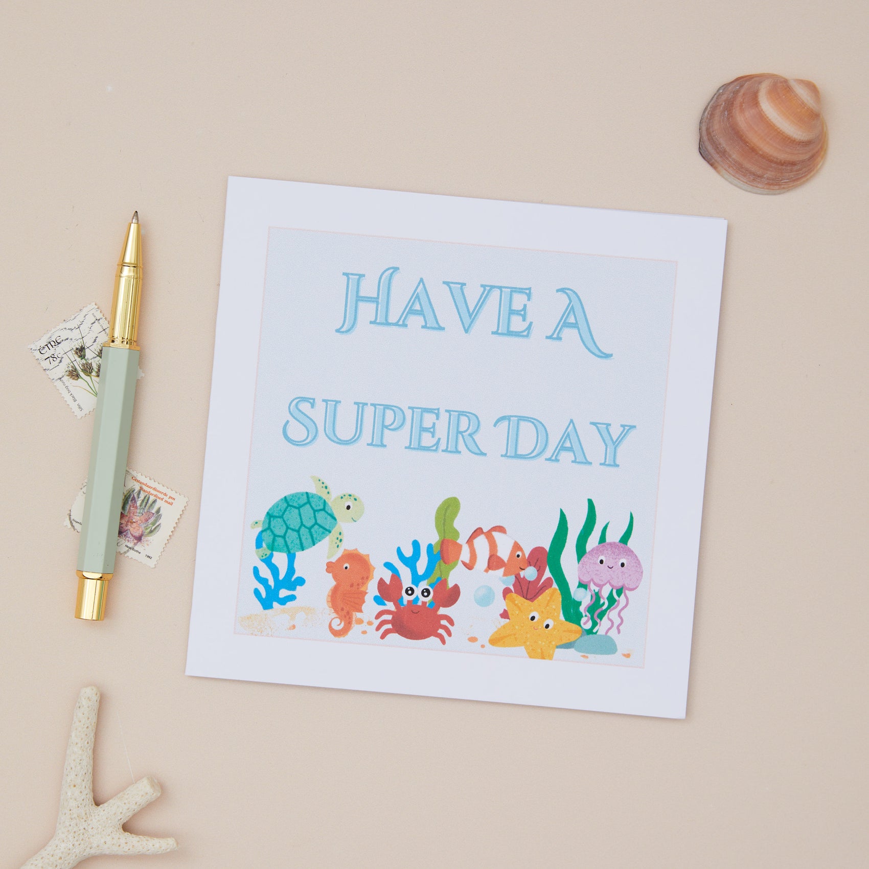 Kids Sealife Birthday Celebration Card with a sea creatures design, titled 'HAVE A SUPER DAY'. The Card is displayed next to a pen and a shell on a neutral background.