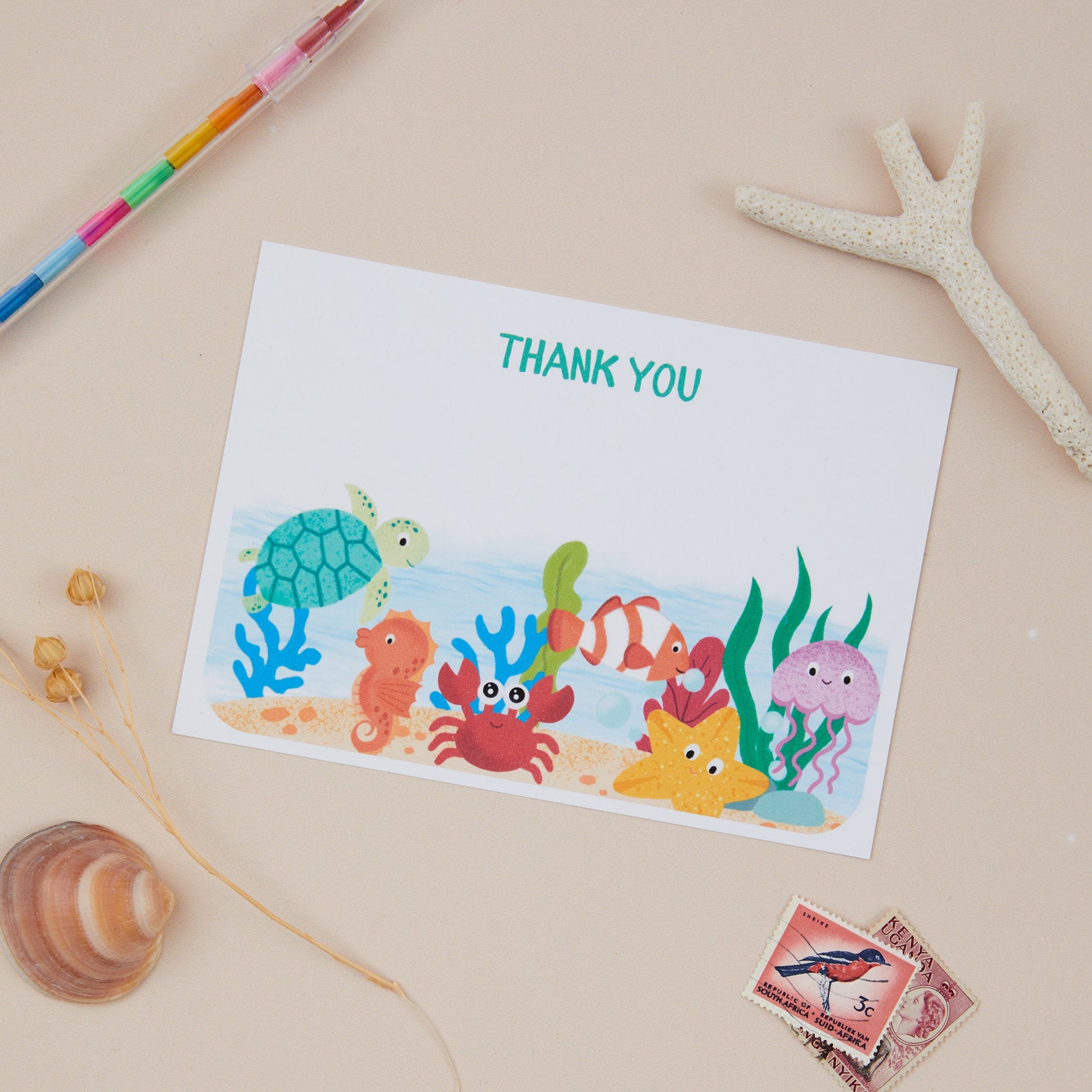 Kids Sealife Postcard Set. A set of 8 flat, sea life themed thank you postcards set with a space for a personalised message on the back, displayed on a neutral background with sealife creature motifs and stationery items.