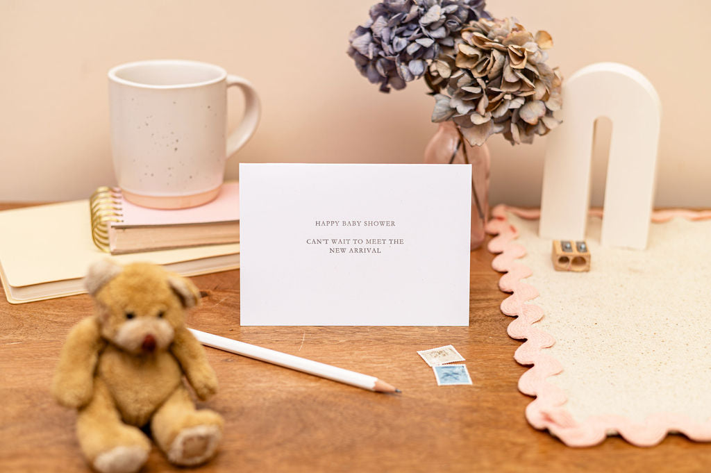 Letterpress Happy Baby Shower Card in white with silver font which says happy baby shower, can't wait to meet the new arrival