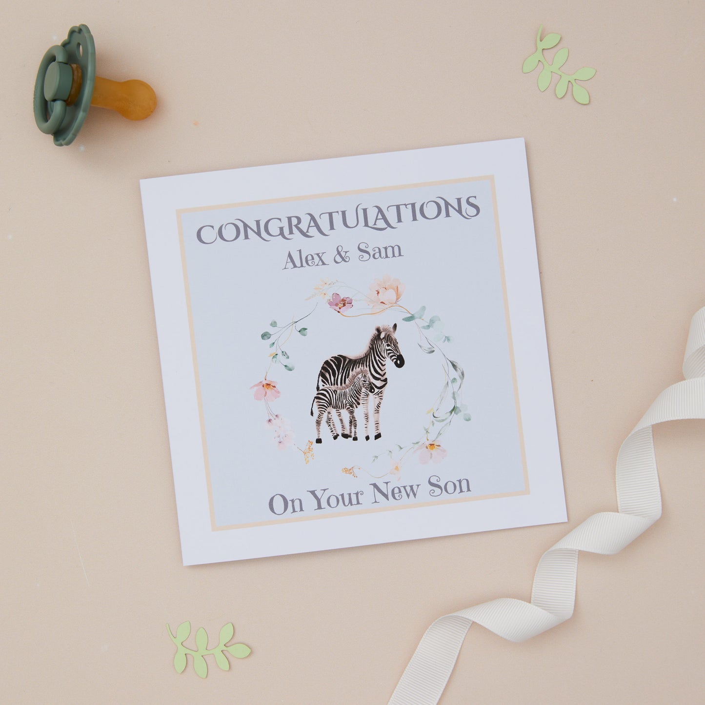 A personalised new baby son card with an illustration of a zebra and its young on a soft blue background, with a yellow border. The card has text congrats on the front and space for a personalized message inside.