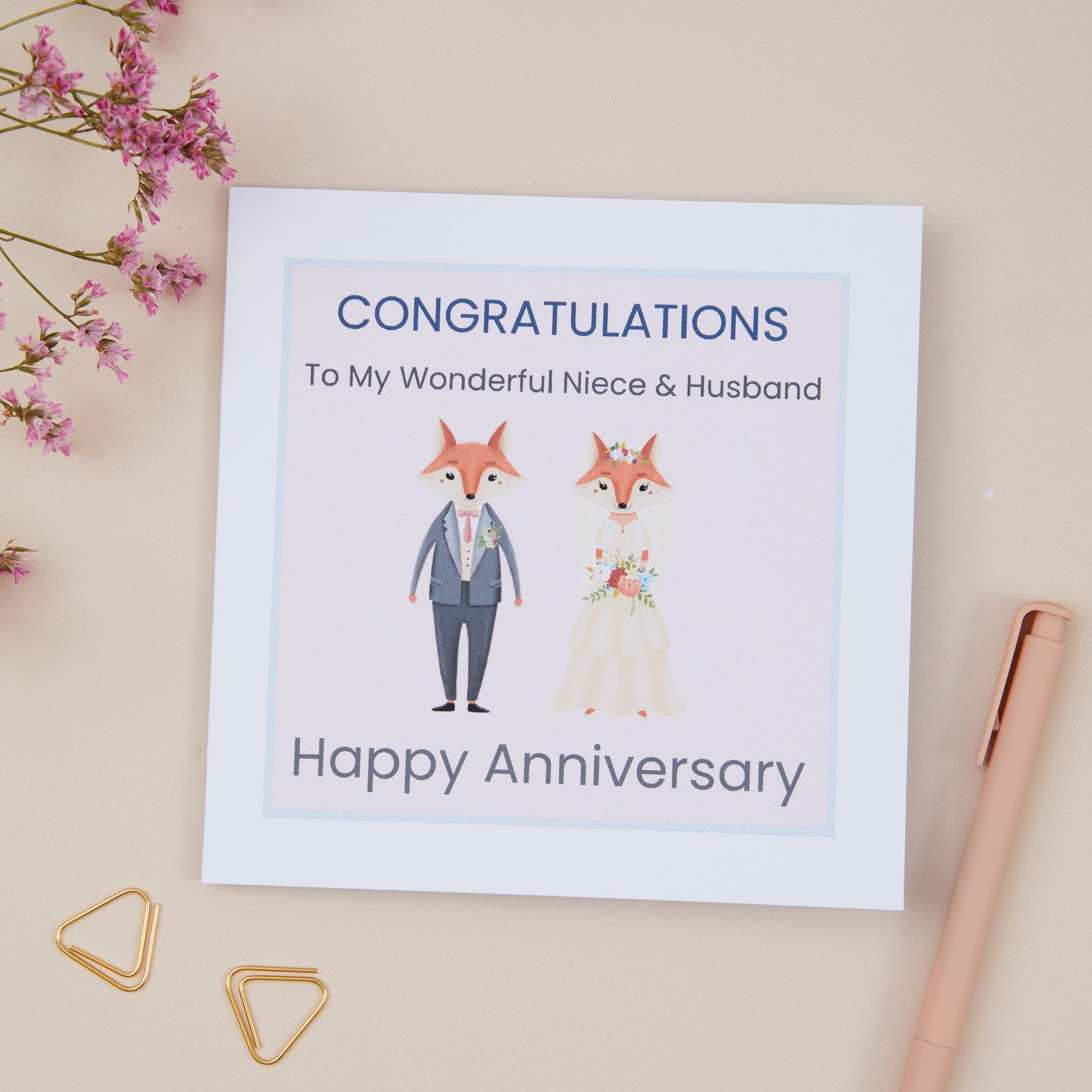 Niece And Husband Anniversary Card with an illustration of a Mr. and Mrs Fox. The text says "congratulations to my wonderful niece and husband, happy Anniversary". The card is placed on a neutral background