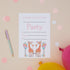 Party Giraffes Childrens ready to write birthday invites. 2 Giraffes with balloons around them on a beige background. The text reads Please join us for a party