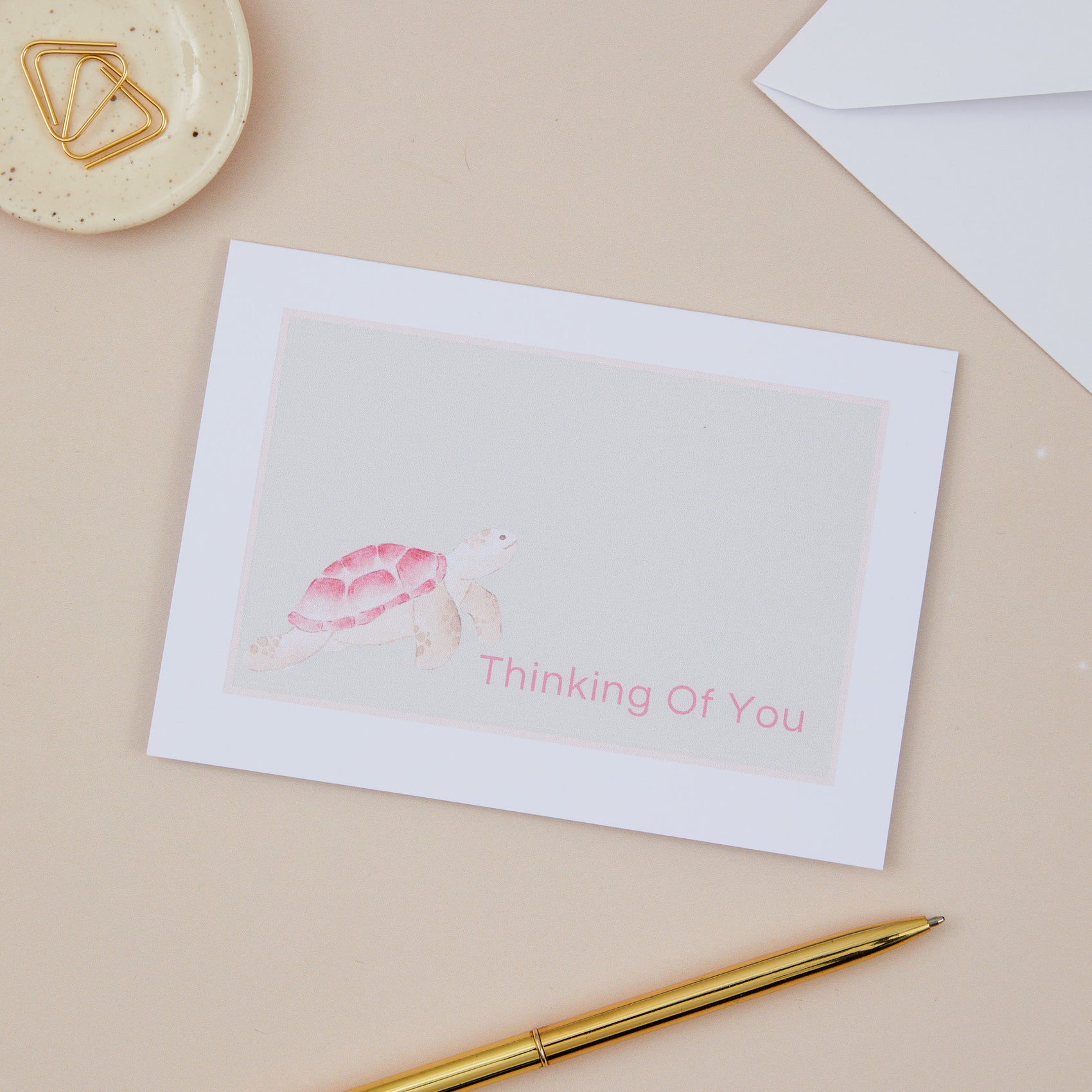 A greeting card with a turtle illustration and the text 'Thinking Of You' on the front, displayed on a neutral background.