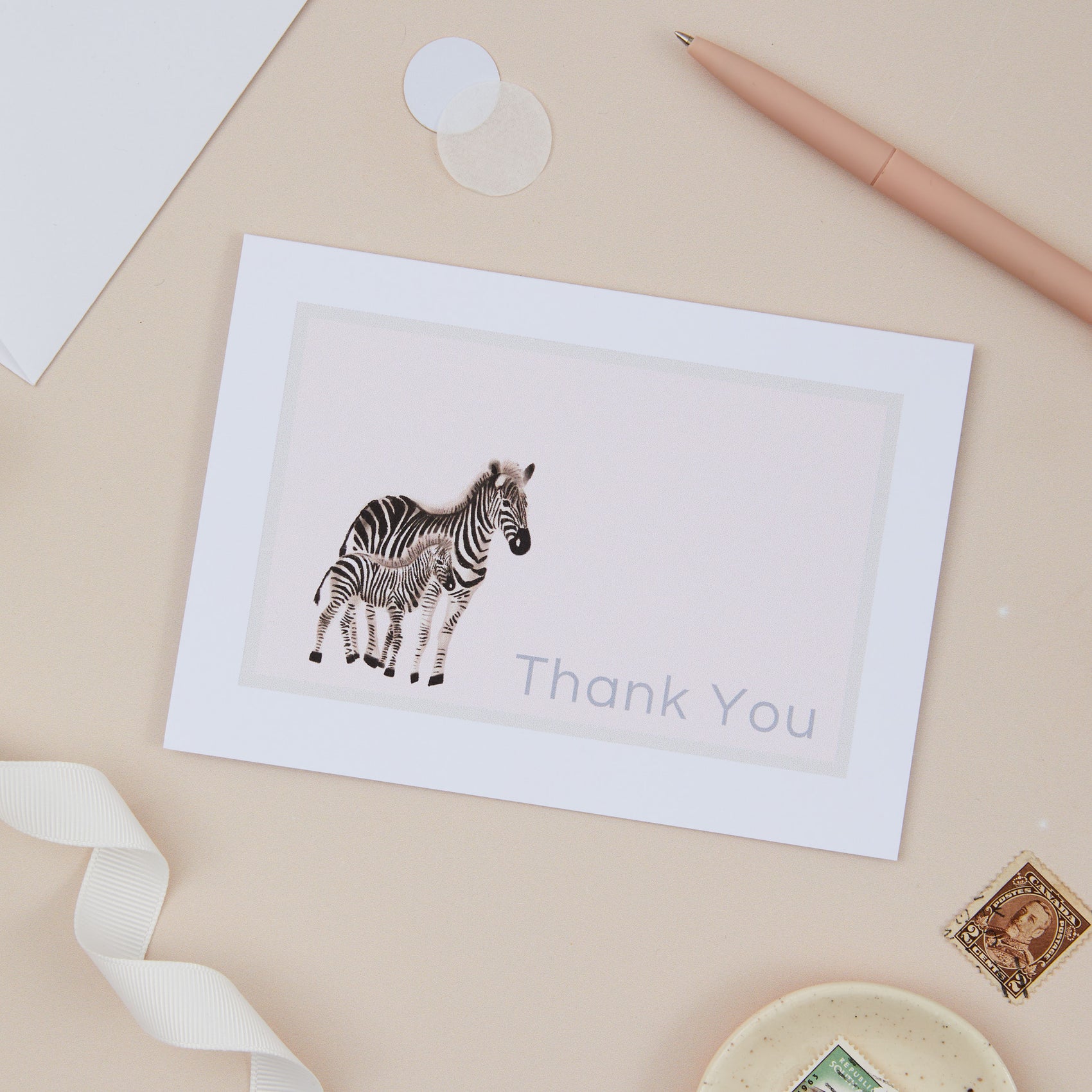 Zebra Thank you card. Thank you card with a Zebra and its young baby. The card says "thankyou". The Zebra is set against a light hue beige background with stationery around it 
