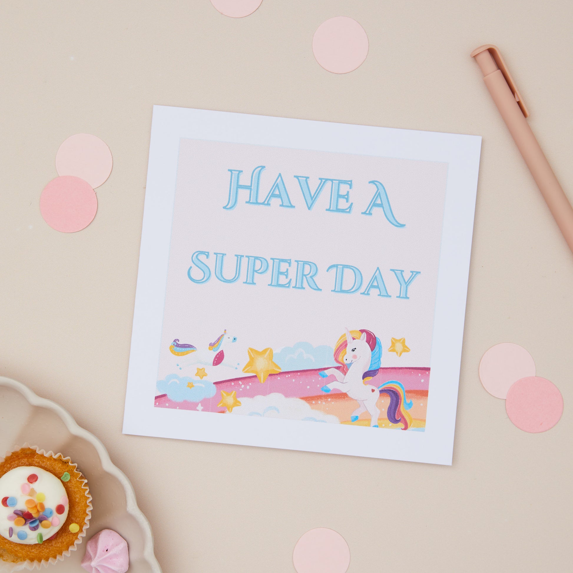 Unicorn Kids Birthday Celebration Card with a colourful illustration of a Unicorn and the text 'HAVE A SUPER DAY' on it, displayed on a neutral background with confetti and a cupcake.