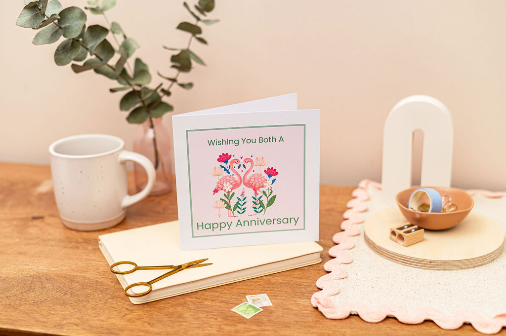 Happy Anniversary Card with a Flamingo pair on a soft pink background.
