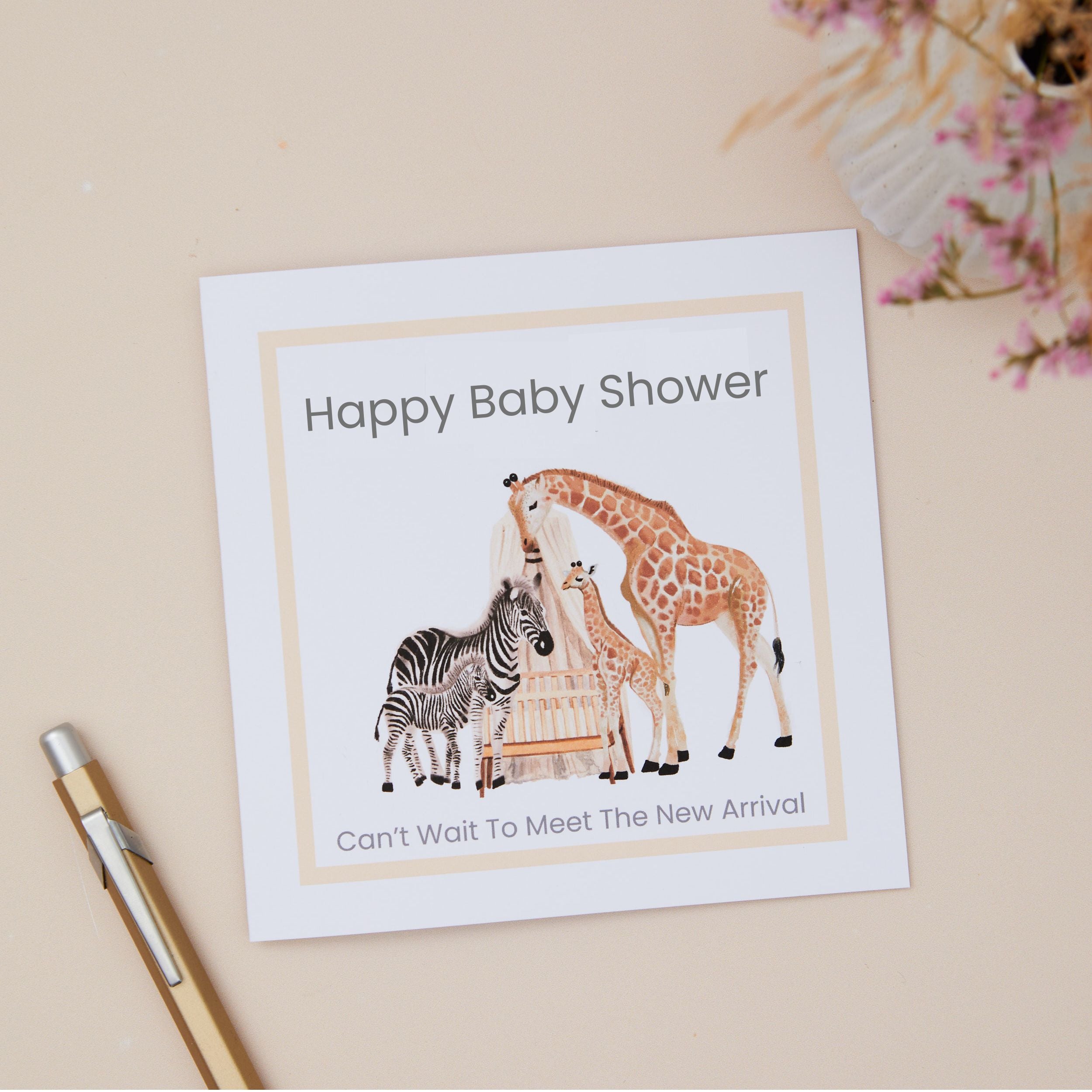Baby shower card featuring young animals. The Card says "Happy Baby Shower, Can't wait to meet the new arrival. The Card sits on a beige background, with a formal pen and dried flowers in a vase next to it.